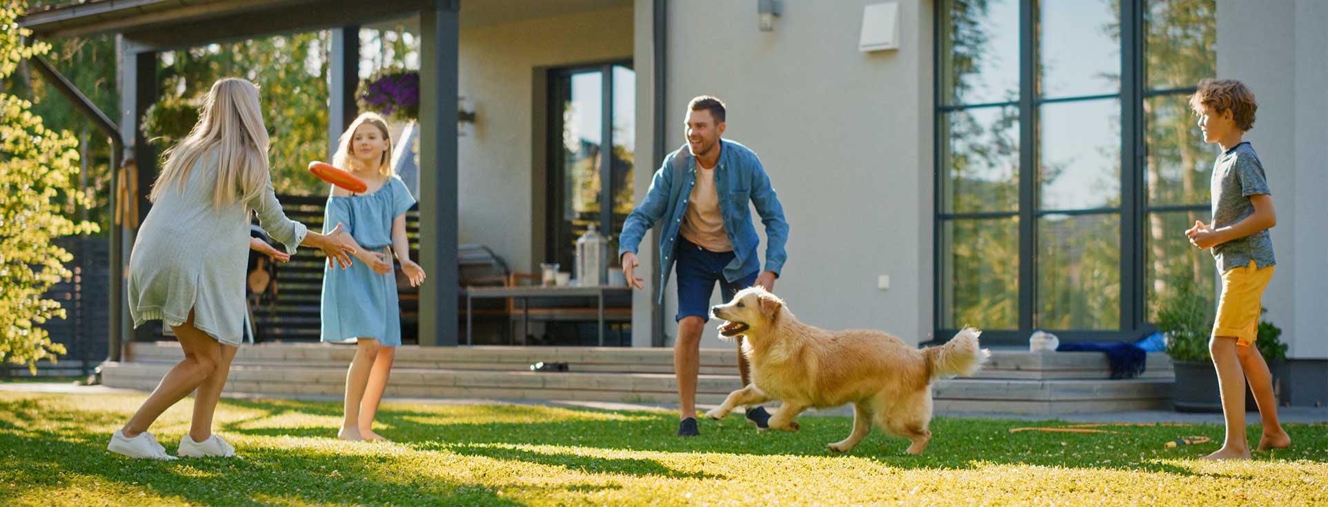 Family playing frisbee in yard with their dog